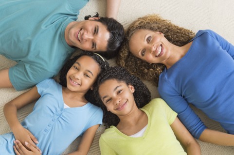 Portrait of parents with daughters (10-13) lying on floor.