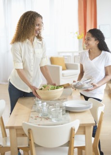 Mother with daughter (10-11) setting table.
