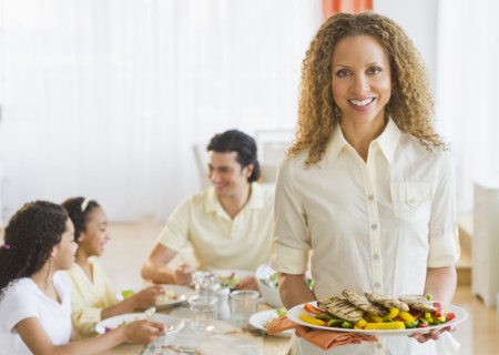 Woman holding dinner plate, with husband and daughters (10-13) in background.
