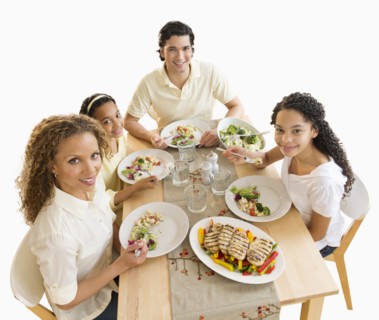 Portrait of parents with daughters (10-13) eating dinner.