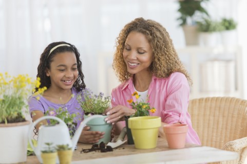 Mother with daughter (12-13) potting flowers.