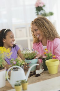 Mother with daughter (12-13) potting flowers.