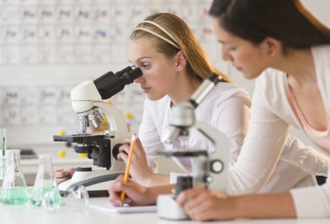Students (16-19) in chemistry lab using microscope.
