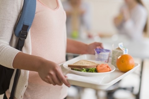 Female student carrying tray in cafeteria.