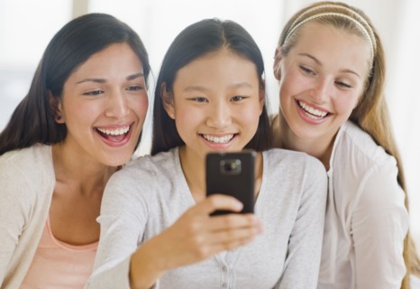 Friends (14-19) looking at mobile phone.