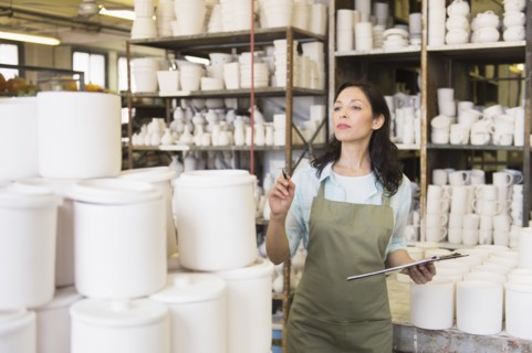 Woman with checklist in pottery warehouse.