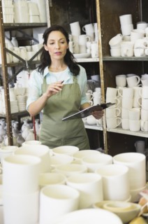Woman with checklist in pottery warehouse.