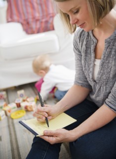 Mother doing notes, son (6-11 months) playing in background. 
Photo : Jamie Grill