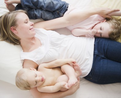 Mother and children (6-11 moths, 2-3) lying in bed. 
Photo : Jamie Grill