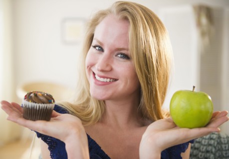Woman holding apple and cupcake. 
Photo: Jamie Grill