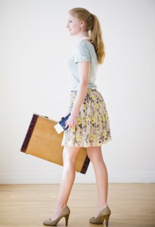 Woman holding suitcase and passport. 
Photo : Jamie Grill