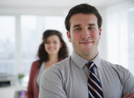Portrait of business man, business woman in background. 
Photo : Jamie Grill