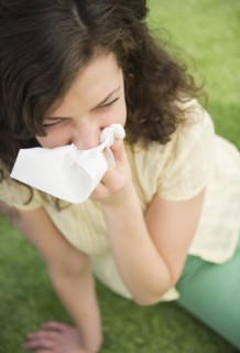 Woman blowing nose while sitting on lawn. 
Photo : Jamie Grill