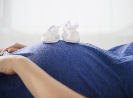 Pregnant woman with baby boots on belly. 
Photo: Jamie Grill