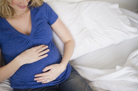 Pregnant woman sitting in bed. 
Photo : Jamie Grill