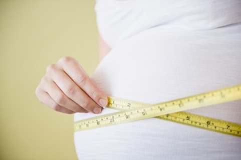 Pregnant woman measuring belly with tape measure. 
Photo : Jamie Grill