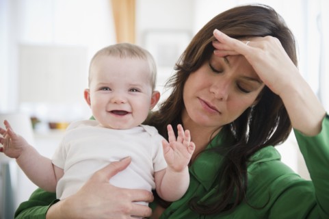 Tired mother holding baby daughter (6-11 months). 
Photo : Jamie Grill