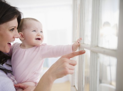 Mother with baby daughter (6-11 months) looking through window. 
Photo : Jamie Grill