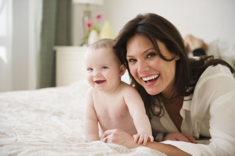 Mother with baby daughter (6-11 months) lying on bed. 
Photo : Jamie Grill