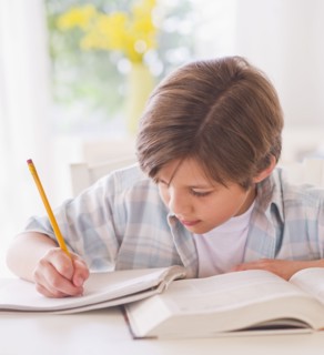 Boy (10-11 years) doing homework at table . 
Photo : Daniel Grill