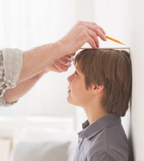 Father measuring son's (10-11 years) height. 
Photo : Daniel Grill