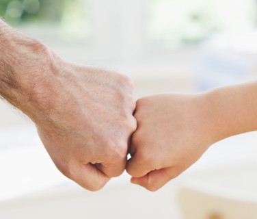 Close up of father's and son's (10-11 years) hands doing fist bump. 
Photo : Daniel Grill