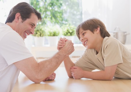 Father and son (10-11 years) arm wrestling. 
Photo: Daniel Grill