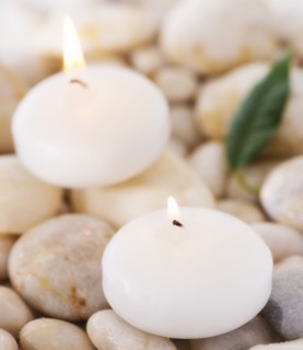 Close up of tea lights and green leaf on pebble stones, studio shot. 
Photo : Daniel Grill