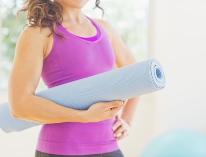 Woman holding rolled up yoga mat. 
Photo: Daniel Grill