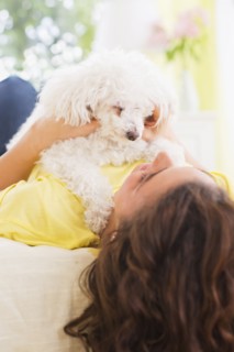 Woman lying on bed with her dog. 
Photo : Daniel Grill