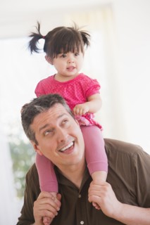 Father carrying baby daughter (12-17 months) on shoulders. 
Photo : Daniel Grill
