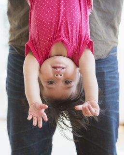 Father holding baby daughter (12-17 months) upside down. 
Photo : Daniel Grill