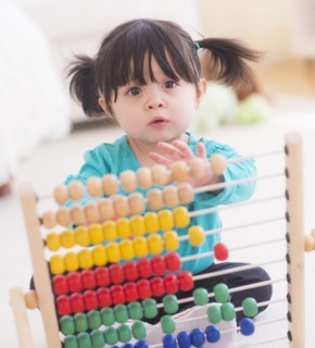 Portrait of baby girl (12-17 months) playing with abacus. 
Photo : Daniel Grill