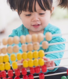 Portrait of baby girl (12-17 months) playing with abacus. 
Photo : Daniel Grill