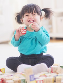 Portrait of baby girl (12-17 months) playing alphabet blocks. 
Photo: Daniel Grill