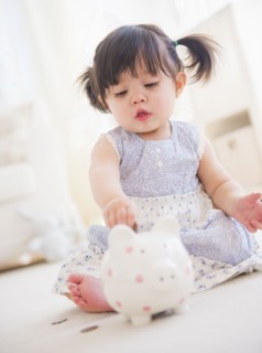 Portrait of baby girl (12-17 months) playing with piggy bank. 
Photo : Daniel Grill