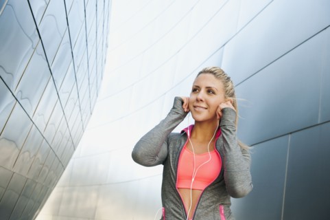 USA, California, Los Angeles, Young woman listening to music on headphones while training.