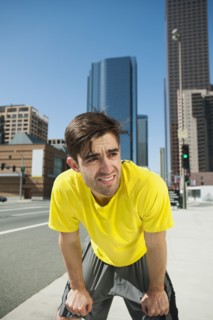 USA, California, Los Angeles, Young man resting after running on city street.