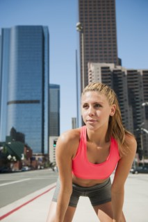 USA, California, Los Angeles, Young woman resting after running on city street.