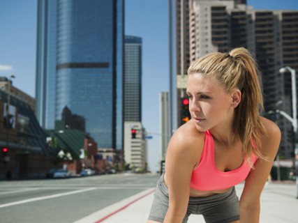 USA, California, Los Angeles, Young woman resting after running on city street.