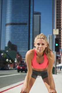 USA, California, Los Angeles, Young woman resting after running on city street.