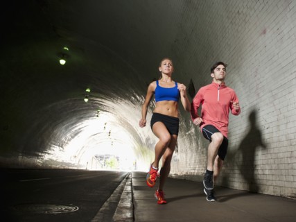 USA, California, Los Angeles, Young man and young woman running in tunnel.