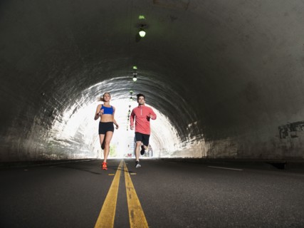 USA, California, Los Angeles, Young man and young woman running in tunnel.