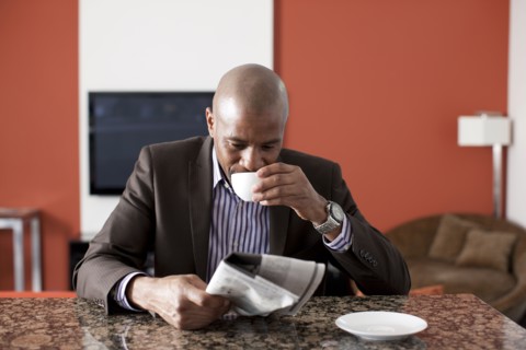 Man enjoying coffee and reading newspaper. 
Photo : Dan Bannister