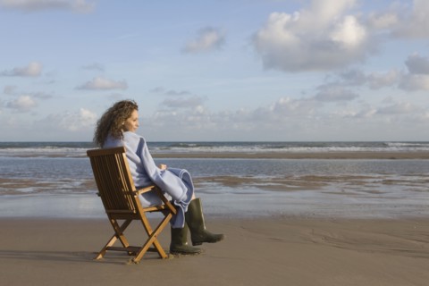 France, Pas-de-Calais, Escalles, Young woman sitting on chair on empty beach. 
Photo : Jan