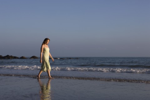 France, Pas-de-Calais, Escalles, Young woman strolling on empty beach. 
Photo: Jan Scherders