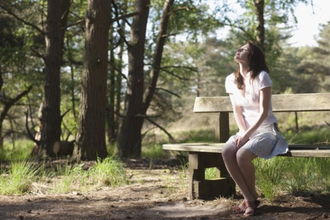 Belgium, Kalmthoutse Heide, Young woman sitting on bench. 
Photo : Jan Scherders