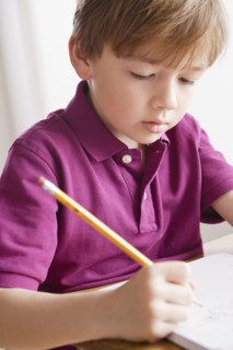 Schoolboy focused on writing in classroom. 
Photo : Rob Lewine