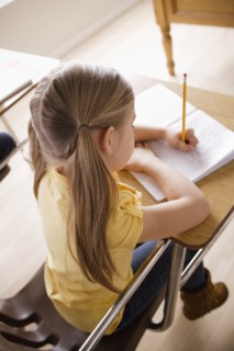 Schoolgirl focused on writing in classroom. 
Photo: Rob Lewine