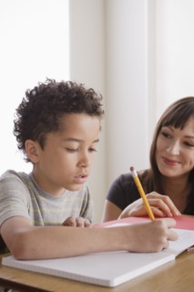 Pupil writing together with teacher. 
Photo : Rob Lewine